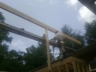 Carpenter setting a ridge beam over a new addition frame — Ice Dam Removal by Roofing Brothers in Street