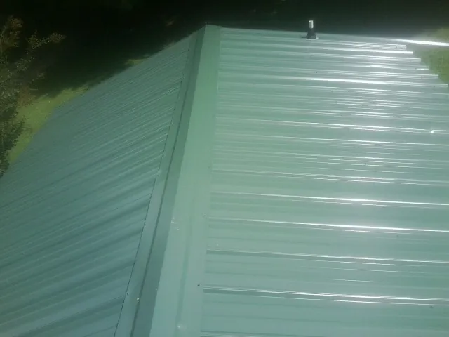 New green metal panels meeting at the ridge of a roof — Flat Roof Repair work by our crew in Street