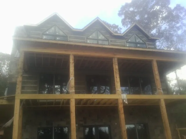 Dormers and porch framing on a large log home under construction — Roof Coating work by our crew in Street