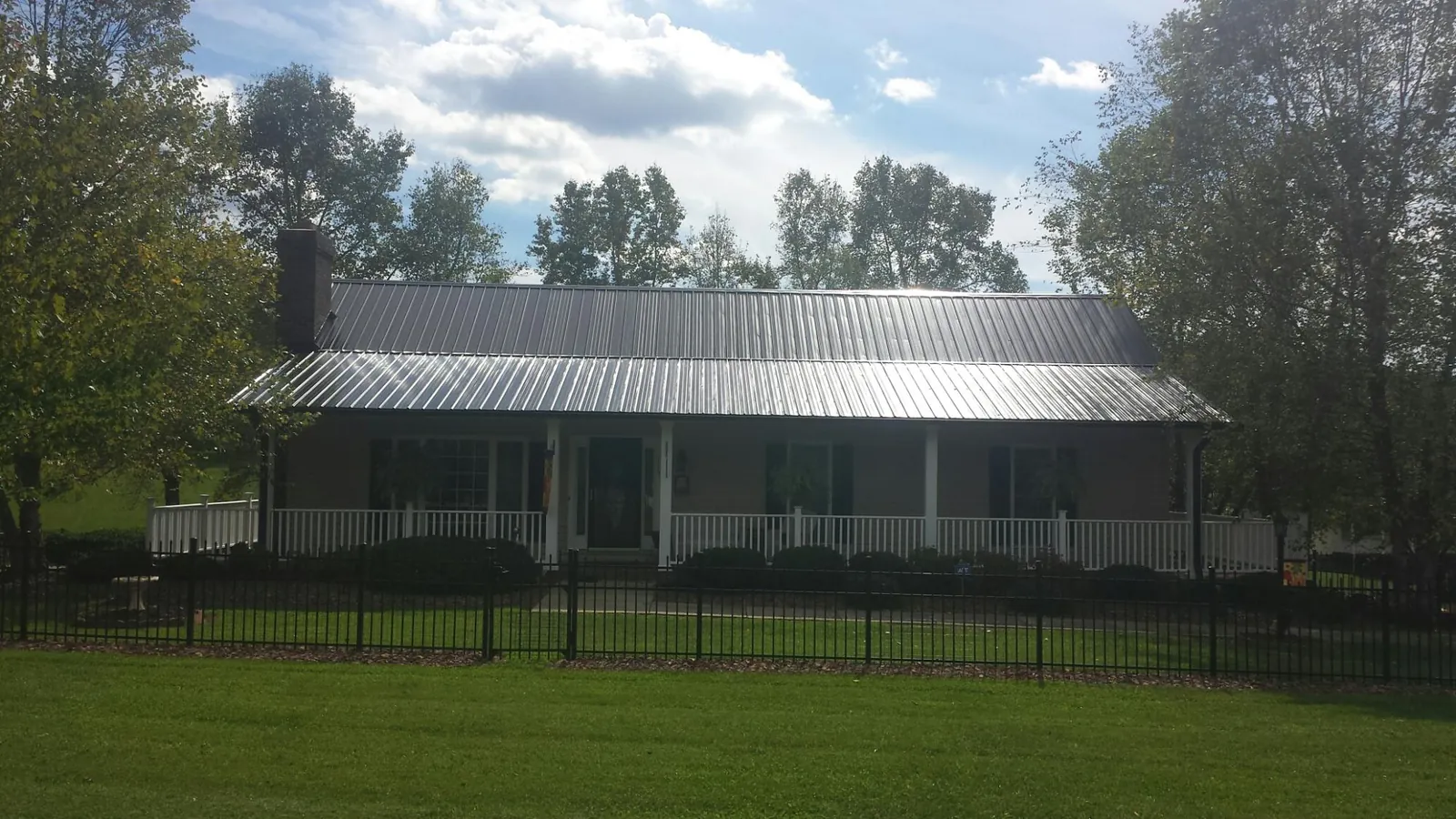 Gray metal roof on a brick ranch with a full width front porch — Gutter Guard Installation work by our crew in Street