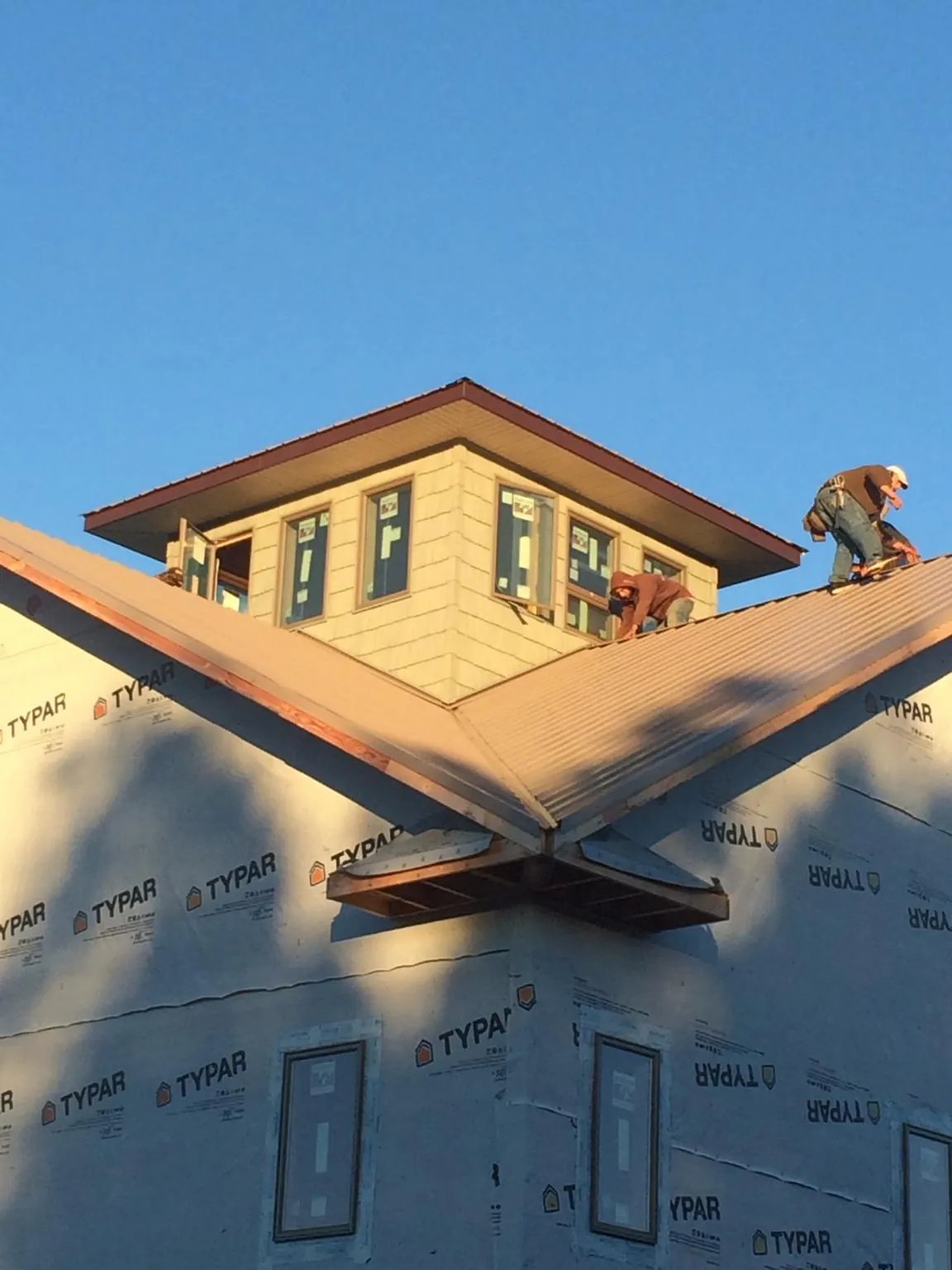 Roofers working around a rooftop cupola on a new metal roof at sunset — Roof Waterproofing in Street by Roofing Brothers